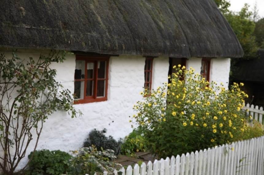 A white house with a thatched roof
Description automatically generated